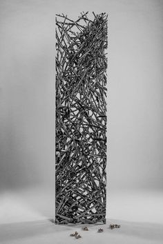 an abstract sculpture made out of sticks and nails in black and white, against a gray background