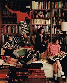 several people sitting on a couch in front of bookshelves