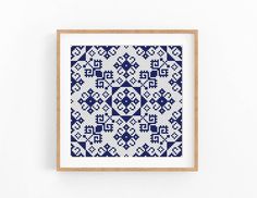 a blue and white cross - stitch pattern in a wooden frame hanging on a wall