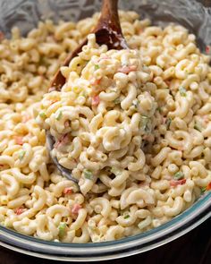 macaroni and cheese is being stirred with a wooden spoon in a glass bowl