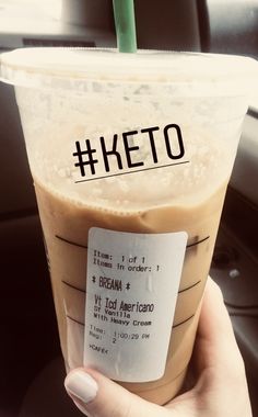 a person holding up a drink with the name keto written on it in front of their face