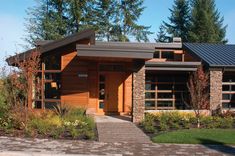 a modern house with stone and wood accents in the front yard, surrounded by greenery