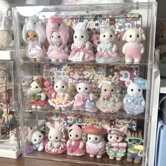 many small stuffed animals are on display in a clear case, with other toys behind them