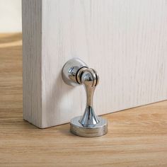 a close up of a door handle on a white wooden door with wood grained flooring