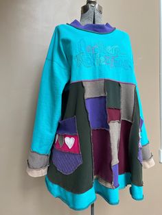 a blue jacket with patches and hearts on the front is hanging up against a wall