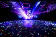 an empty dance floor with colorful lights and confetti on the ground in front of it