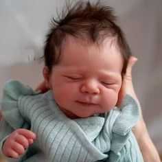 a woman holding a baby in her arms and touching it's head with both hands