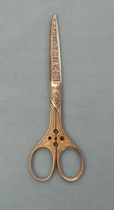 an old pair of gold scissors on a gray background