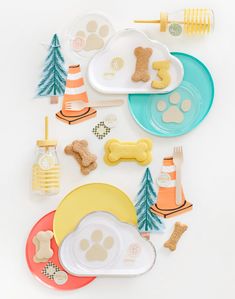 dog themed party supplies including plates, cups and forks on a white surface with trees in the background