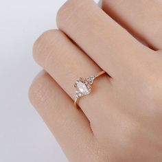 a woman's hand with a diamond ring on top of her finger and the other hand holding an engagement ring