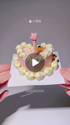 someone is holding up a cake with a candle in it's center, and the video appears to be playing