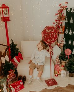 a little boy sitting on top of a white couch next to a christmas tree and a stop sign