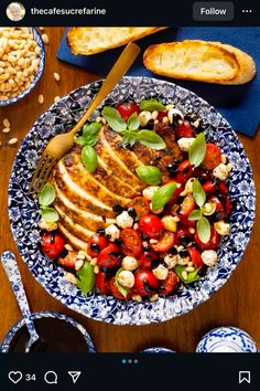 a blue and white plate topped with meat and vegetables next to toasted baguettes