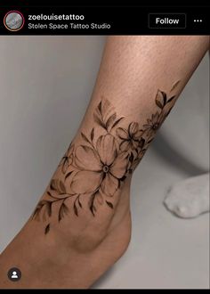 a close up of a person's foot with flowers tattooed on the bottom of it