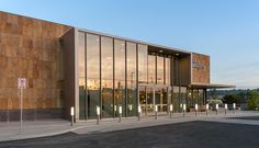 an empty parking lot in front of a building with glass walls and doors on both sides