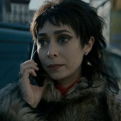 a woman talking on a cell phone while wearing a fur coat