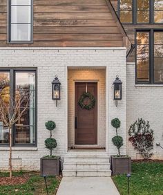 a white brick house with black shutters and wreath on the front door is shown