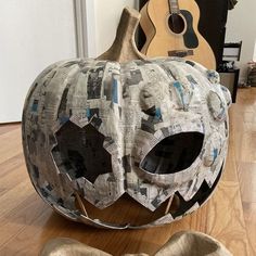 a large pumpkin sitting on top of a hard wood floor next to a wooden guitar