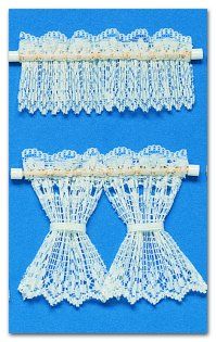 three white lace curtains hanging on a blue wall