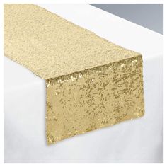 a gold table runner on top of a white table with sequins and glitter