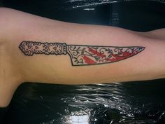 a tattoo on the arm of a woman with a knife in it's center