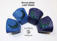 four purple and green glittered leather ear covers with crescent moon design on them, set against a white background