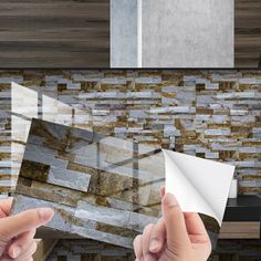 two hands are holding papers in front of a stone wall