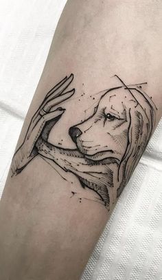 a black and white tattoo on the arm of a person holding a dog's head