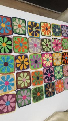 there are many crocheted squares that have flowers on them, and one is hanging from the wall