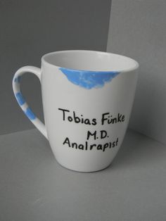 a white coffee cup with blue and white designs on it that says, tobias finke m d analrapist