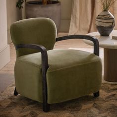 a green chair sitting on top of a rug next to a table and potted plant