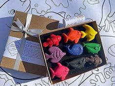 a box filled with lots of different colored toy animals sitting next to a paper bag