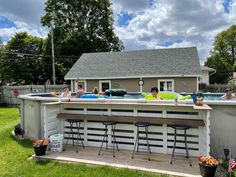 people in an above ground pool surrounded by lawn chairs and umbrellas, with one person sitting at the bar