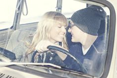 a man and woman sitting in the driver's seat of a car looking at each other