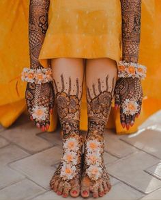 the legs and feet of a woman with henna tattoos on their feet, decorated with flowers