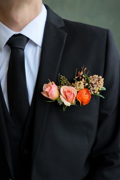 a man in a black suit with flowers on his lapel