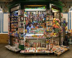 a man is standing in front of a store with many items on the shelves and around it