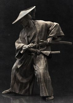 a black and white photo of a statue holding a stick