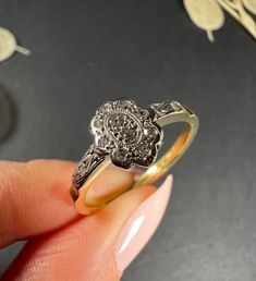 a woman's hand is holding an antique diamond ring