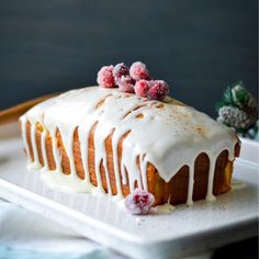 a bundt cake with icing and cranberries on top sitting on a plate