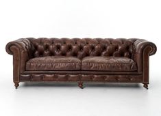 a brown leather couch sitting on top of a white floor