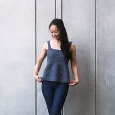 a woman standing in front of a wall with her hands on her hips and smiling