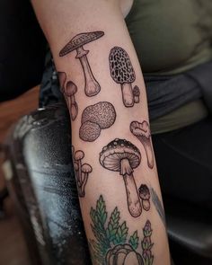 a woman's arm with tattoos on it that include mushrooms, leaves and flowers