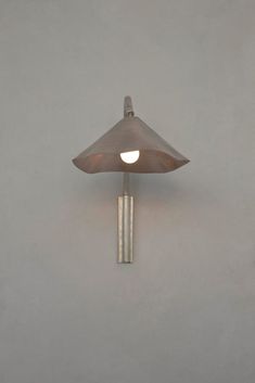 a wall mounted lamp on the side of a gray wall with a white light in front of it