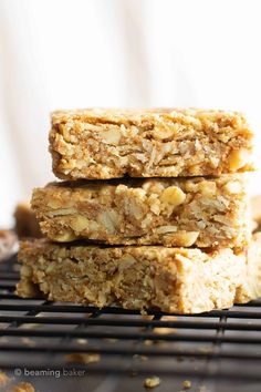 three granola bars stacked on top of each other with nuts and oats in the background