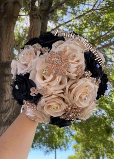 a bridal bouquet is being held by a woman's hand in front of a tree