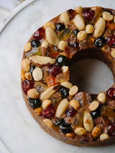 a bundt cake with nuts and dried fruit on it sitting on a white plate