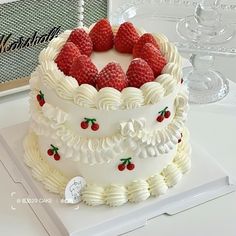 a cake with white frosting and strawberries on top is sitting on a table