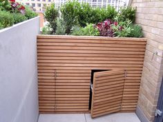 a wooden planter on the side of a building with plants growing out of it