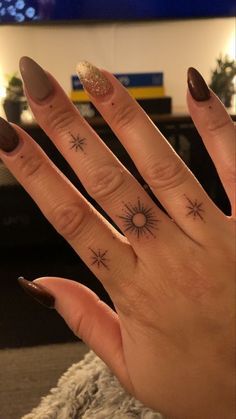 a woman's hand with two small stars tattooed on the middle of her fingers